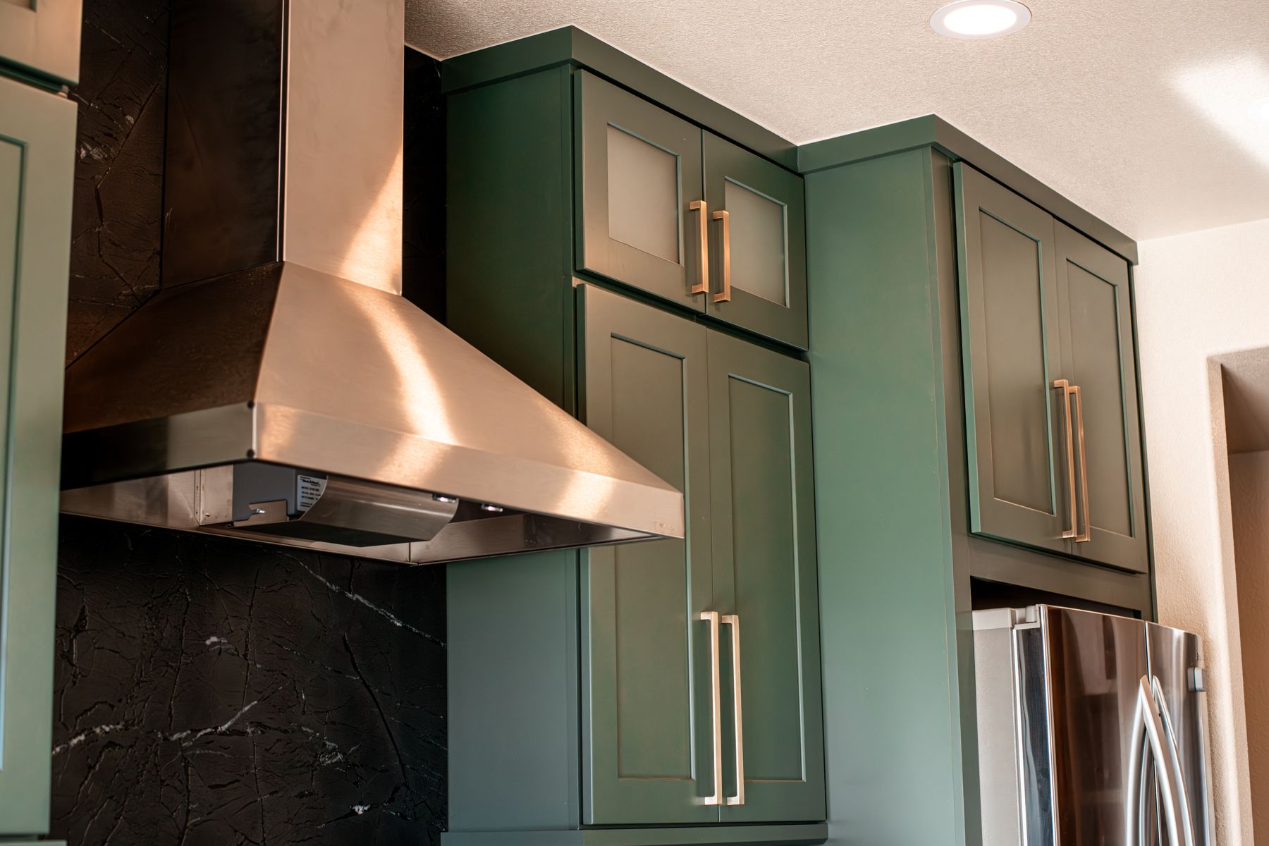 Copper hood and green cabinetry in a finished Revive kitchen